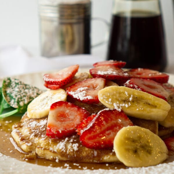 Pancakes topped with sliced strawberries, bananas, powdered sugar, and syrup at Lincoln Grill Cafe.